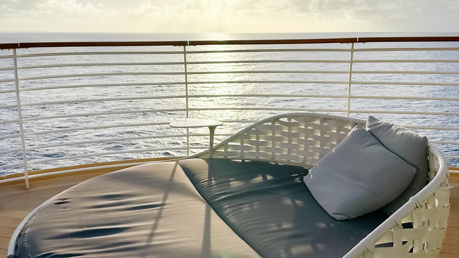 A cushioned daybed on a cruise ship verandah overlooking the sea